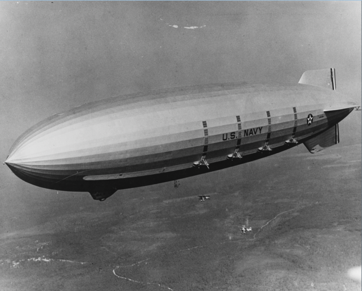 An old photo of a large blimp flying in the air.